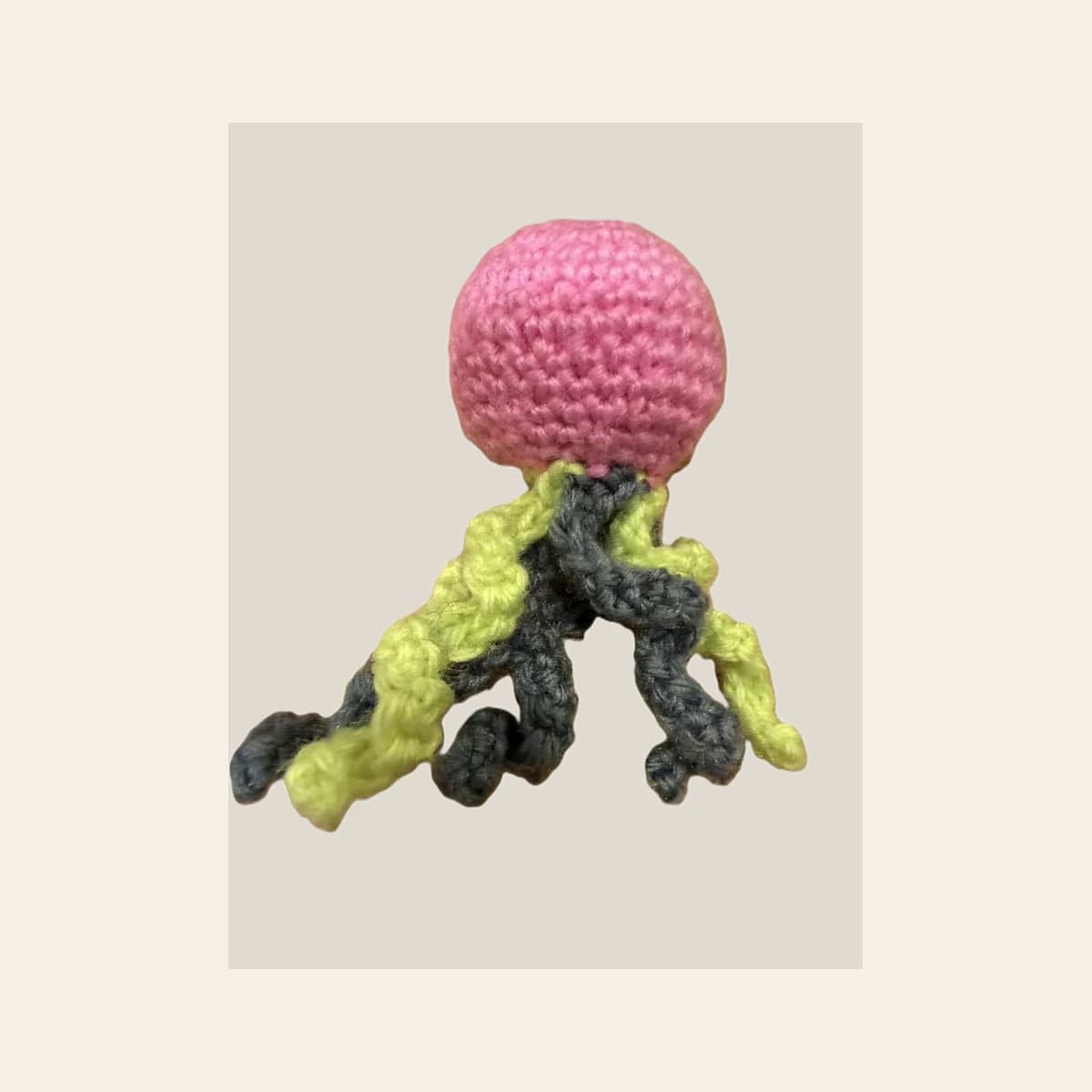 A small crocheted octopus sample photographed on a warm neutral background.